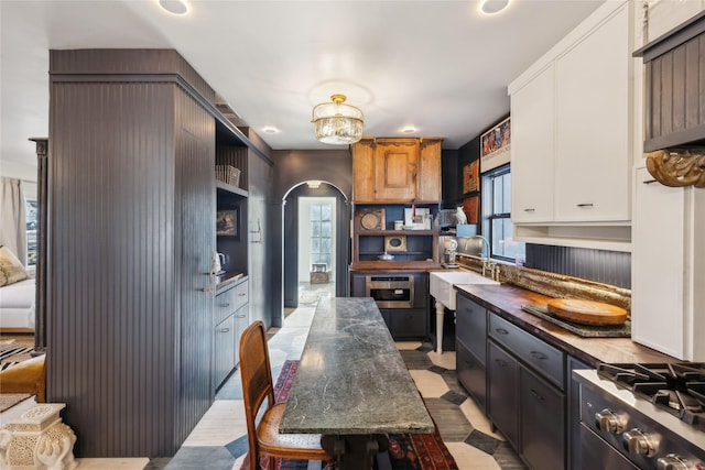 kitchen with stainless steel range oven, sink, and white cabinetry