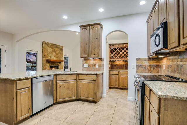 kitchen featuring light tile patterned floors, decorative backsplash, light stone countertops, and stainless steel appliances