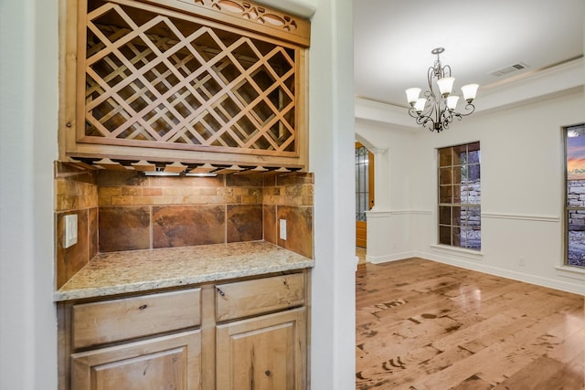 wine room featuring light hardwood / wood-style flooring, crown molding, and a chandelier