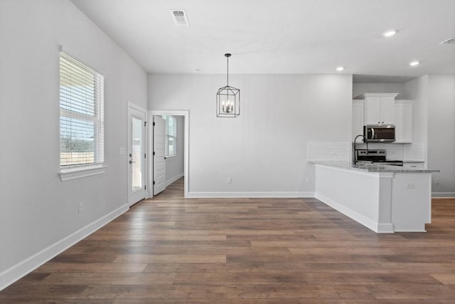 kitchen featuring pendant lighting, stainless steel appliances, light stone countertops, white cabinets, and kitchen peninsula