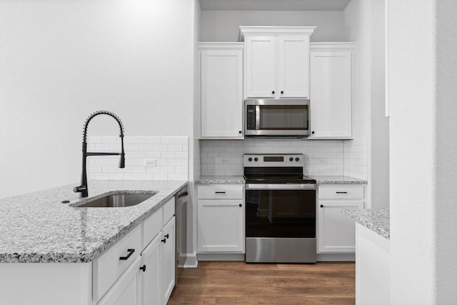 kitchen featuring sink, appliances with stainless steel finishes, white cabinetry, backsplash, and light stone counters