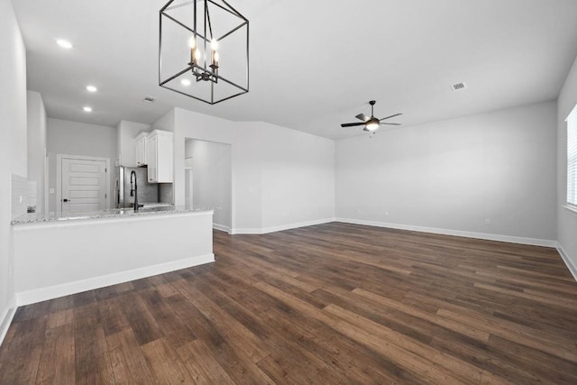 unfurnished living room with dark hardwood / wood-style flooring and ceiling fan