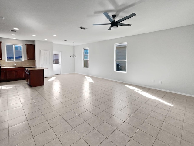 unfurnished living room featuring ceiling fan with notable chandelier and light tile patterned flooring