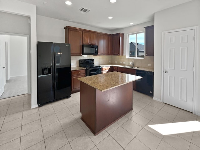 kitchen featuring light stone countertops, light tile patterned floors, a center island, and black appliances