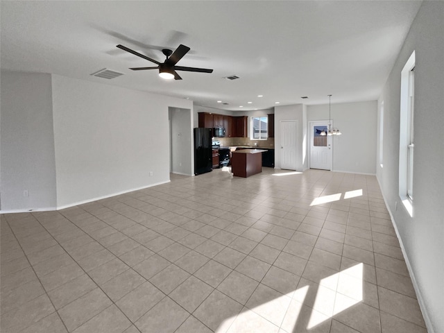 unfurnished living room featuring light tile patterned flooring and ceiling fan with notable chandelier