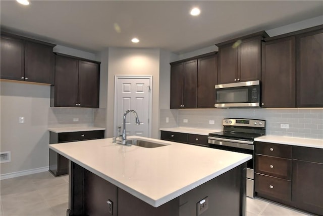 kitchen featuring dark brown cabinets, sink, stainless steel appliances, and a center island with sink