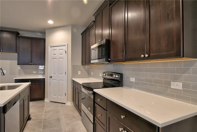 kitchen with stainless steel appliances, sink, backsplash, light tile patterned flooring, and dark brown cabinets