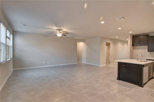 kitchen featuring ceiling fan, stainless steel dishwasher, sink, dark brown cabinetry, and a kitchen island with sink