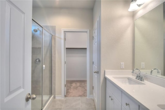 bathroom featuring a shower with shower door, vanity, and tile patterned flooring