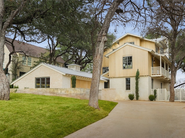 view of front of house featuring a balcony and a front lawn