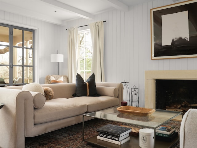 living room featuring beam ceiling, a fireplace, and wood walls