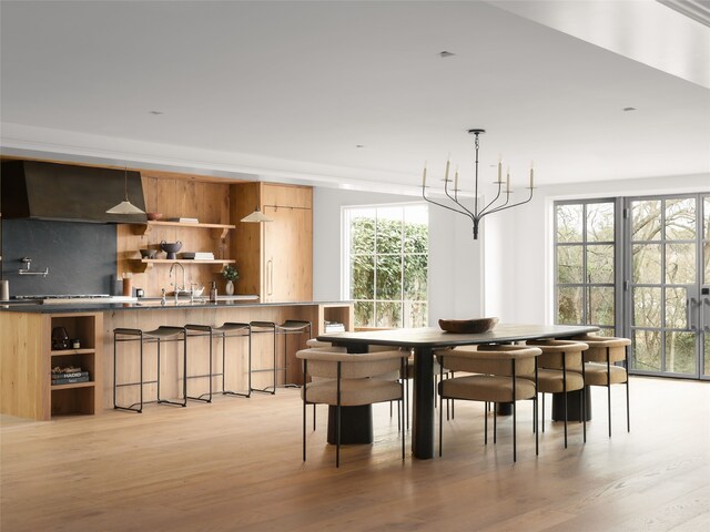 dining area featuring a notable chandelier, sink, and light hardwood / wood-style floors