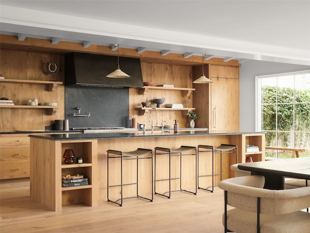 kitchen with decorative light fixtures, a wealth of natural light, wall chimney exhaust hood, light hardwood / wood-style flooring, and sink