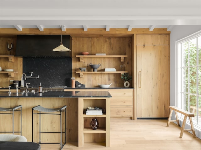 kitchen featuring tasteful backsplash, decorative light fixtures, light wood-type flooring, a breakfast bar, and sink