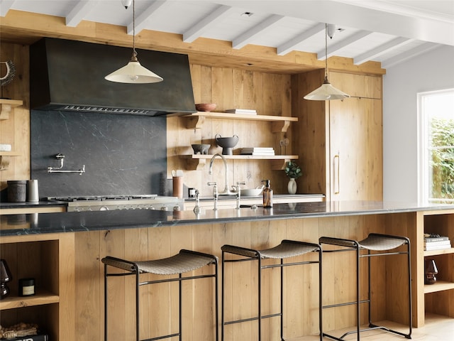 kitchen featuring backsplash, premium range hood, lofted ceiling with beams, hanging light fixtures, and a kitchen breakfast bar