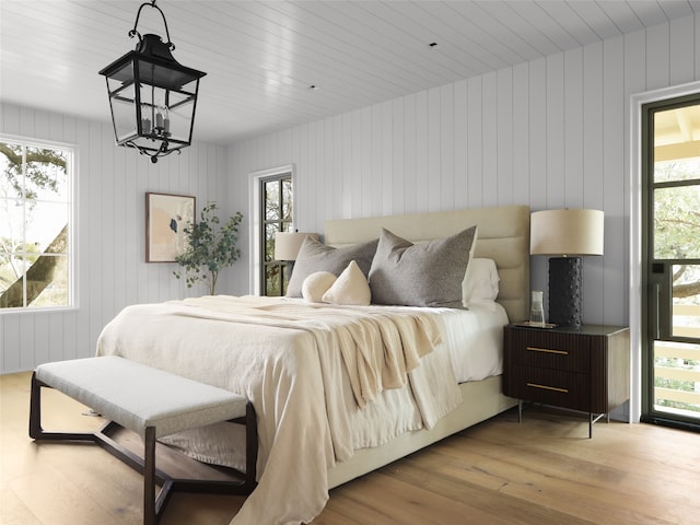 bedroom featuring light wood-type flooring and wood walls