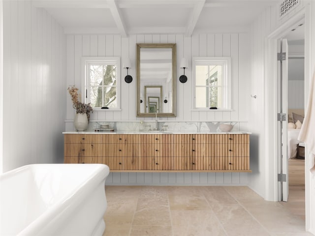 bathroom with a tub to relax in, vanity, beamed ceiling, and a healthy amount of sunlight