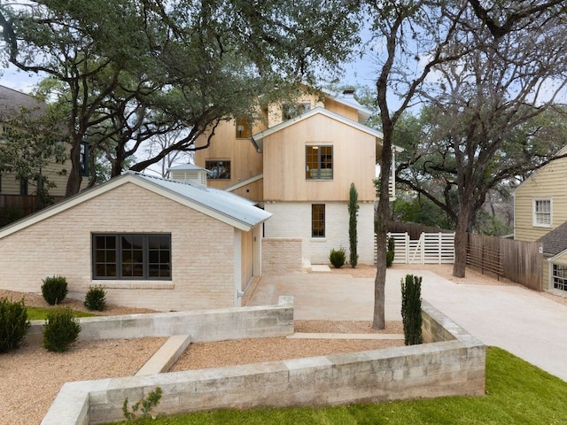 view of front of property with fence, a patio, and brick siding