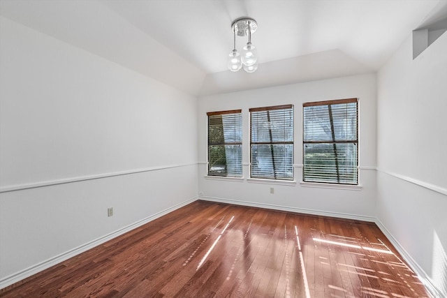 spare room with lofted ceiling, dark hardwood / wood-style floors, and a chandelier