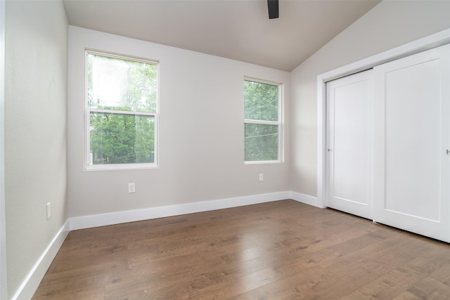 unfurnished bedroom featuring ceiling fan, multiple windows, light hardwood / wood-style flooring, and vaulted ceiling