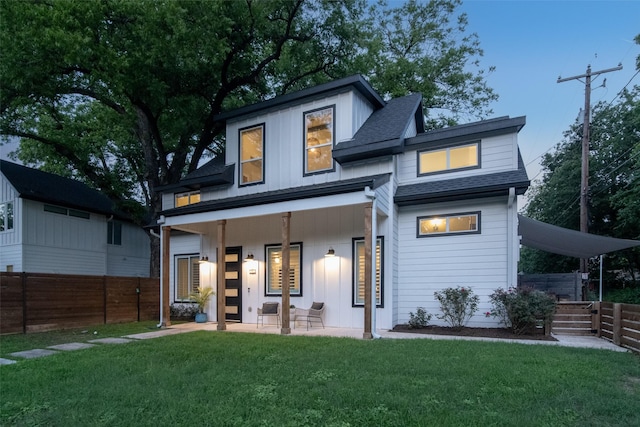 back of property with a lawn and covered porch