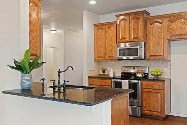 kitchen featuring appliances with stainless steel finishes, decorative backsplash, dark stone counters, and sink