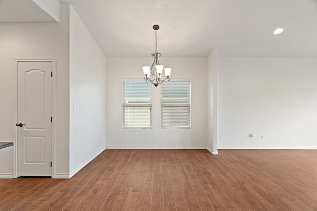 empty room featuring a notable chandelier and hardwood / wood-style flooring