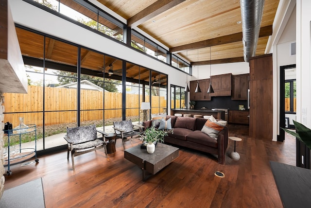 living room with dark wood-type flooring, wooden ceiling, beam ceiling, and a high ceiling