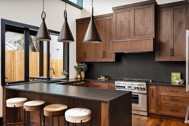 kitchen with tasteful backsplash, stainless steel stove, sink, dark wood-type flooring, and a kitchen breakfast bar