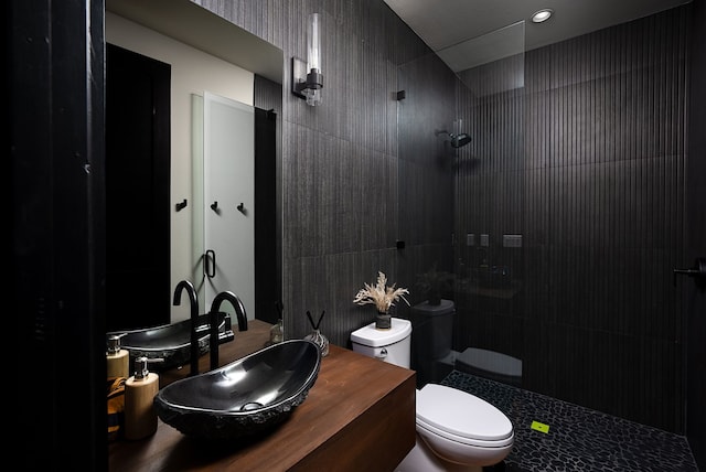 bathroom with toilet, vanity, and a tile shower