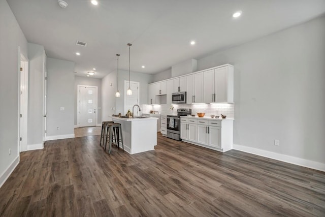 4507 E Martin Luther King Jr Blvd Unit 124, Austin, TX 78721 - kitchen featuring appliances with stainless steel finishes, a sink, an island with sink, white cabinets, and tasteful backsplash