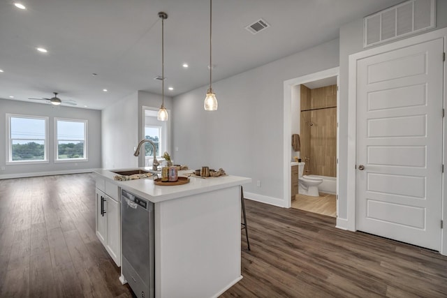 kitchen with pendant lighting, stainless steel dishwasher, sink, white cabinetry, and an island with sink