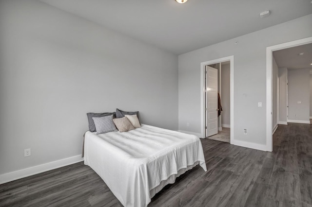 bedroom featuring ensuite bath and dark hardwood / wood-style flooring