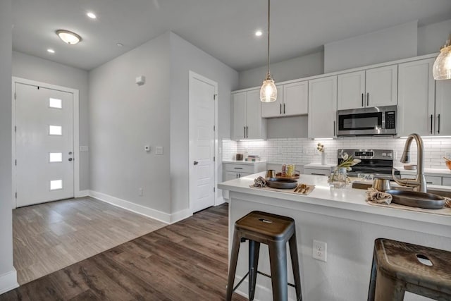 4507 E Martin Luther King Jr Blvd Unit 124, Austin, TX 78721 - kitchen featuring stainless steel appliances, a kitchen breakfast bar, baseboards, decorative backsplash, and recessed lighting