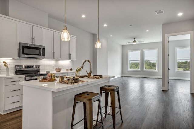 kitchen with white cabinets, appliances with stainless steel finishes, and a center island with sink