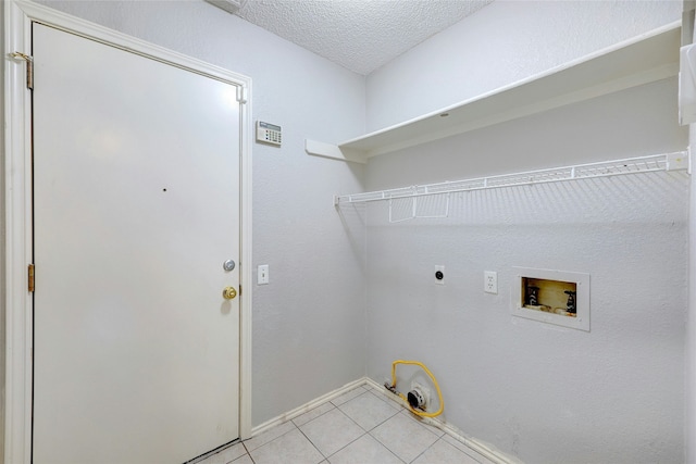 clothes washing area featuring hookup for a gas dryer, light tile patterned flooring, hookup for a washing machine, a textured ceiling, and electric dryer hookup