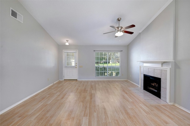 unfurnished living room with ceiling fan, a tiled fireplace, and light hardwood / wood-style flooring