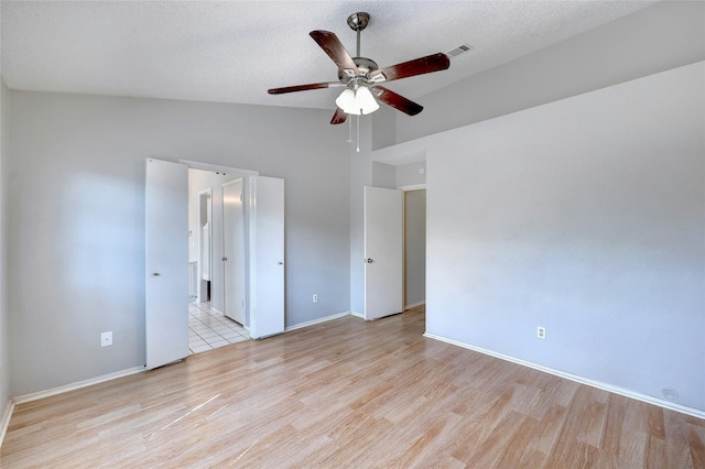 unfurnished bedroom with vaulted ceiling, ceiling fan, a textured ceiling, and light hardwood / wood-style flooring