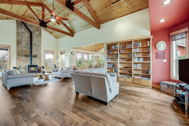 living room with high vaulted ceiling, ceiling fan with notable chandelier, a wood stove, and hardwood / wood-style floors