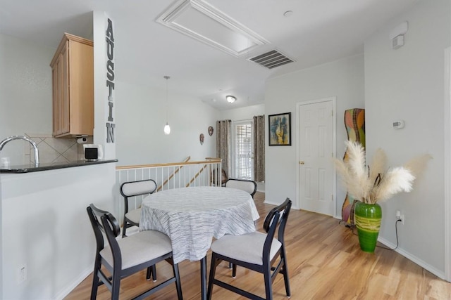 dining space featuring attic access, light wood-type flooring, and baseboards