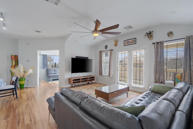 living room featuring vaulted ceiling, light wood-style flooring, and visible vents