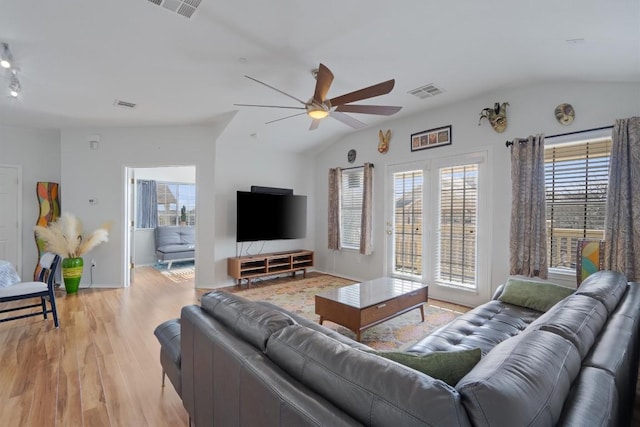 living room featuring lofted ceiling, ceiling fan, light wood-style flooring, and baseboards