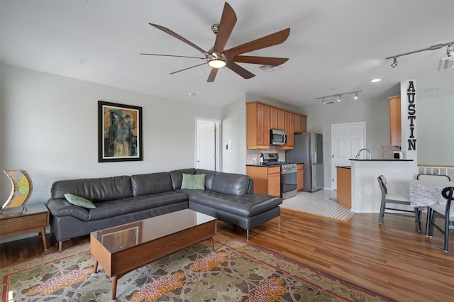 living room featuring ceiling fan, sink, and light hardwood / wood-style flooring