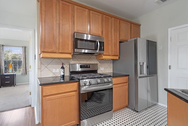 kitchen featuring appliances with stainless steel finishes, decorative backsplash, baseboards, and brown cabinetry