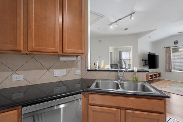 kitchen with dishwasher, a sink, backsplash, and dark countertops