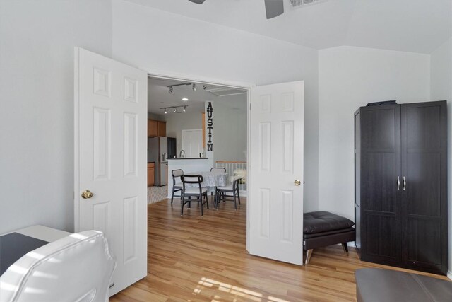 interior space with light wood finished floors, track lighting, stainless steel fridge, and lofted ceiling