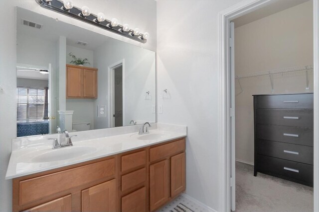 full bath with double vanity, toilet, visible vents, and a sink