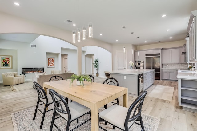 dining room featuring wine cooler, light wood-type flooring, and sink