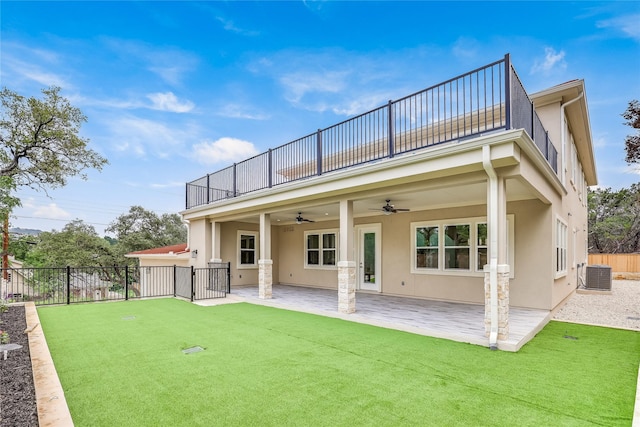 rear view of property featuring central AC unit, ceiling fan, a yard, and a balcony