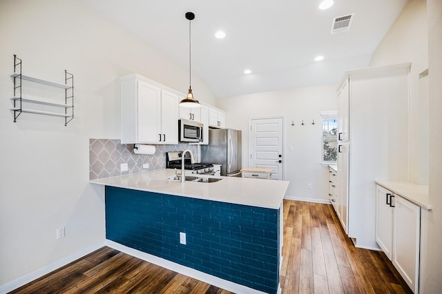 kitchen with decorative light fixtures, kitchen peninsula, sink, white cabinetry, and appliances with stainless steel finishes